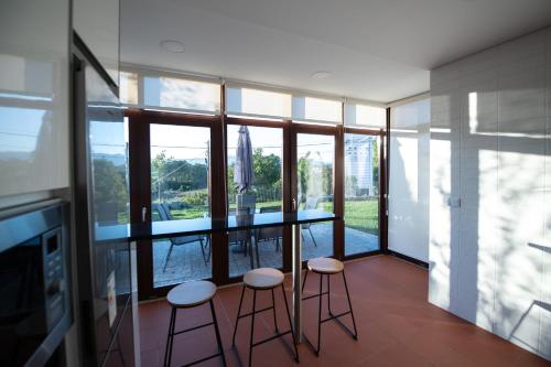 a kitchen with a counter and stools in a room with windows at Casa de Trás-o-Muro in Vila Real