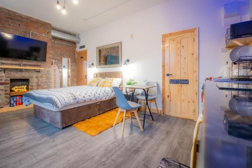 a bedroom with a bed and a table and a fireplace at Renovated Studio - Free Parking - Great Location in Leeds