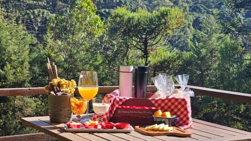 een picknicktafel met eten en drinken en een glas wijn bij Chalé LuNê Vista para a Montanha , Banheira Imersão Externa e Lareira in Gonçalves