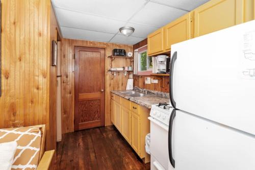 a kitchen with yellow cabinets and a white refrigerator at Chippewa Bluffs Resort Spacious Combined 2BR 2BA Cabins in Barryton