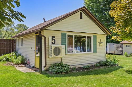 a small yellow house with a large window at Chippewa Bluffs Resort Spacious Combined 2BR 2BA Cabins in Barryton