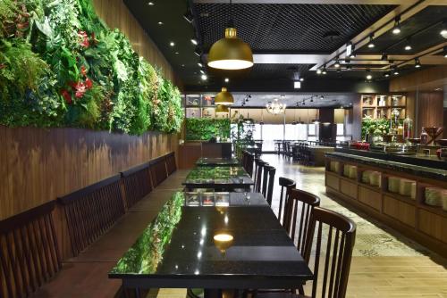 a row of tables in a restaurant with plants on the walls at Just Sleep Kaohsiung Station in Kaohsiung