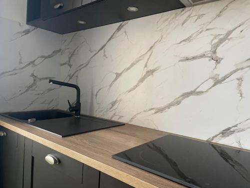 a kitchen counter with a sink and a marble wall at Havre de paix en appartement in Valence