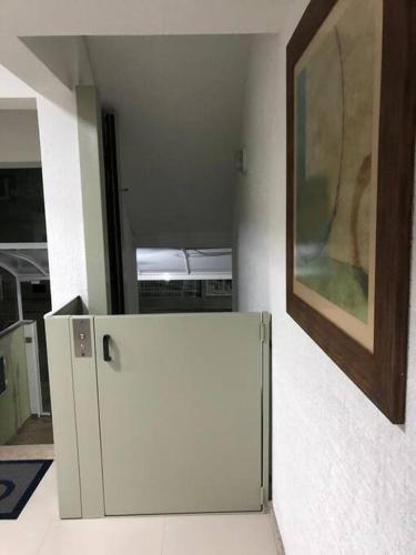 a small white refrigerator in a room with a painting at Apartamento próx ao mar, ao píer O Porto, Hard Rock Café e ao Calçadão Meia Praia in Itapema