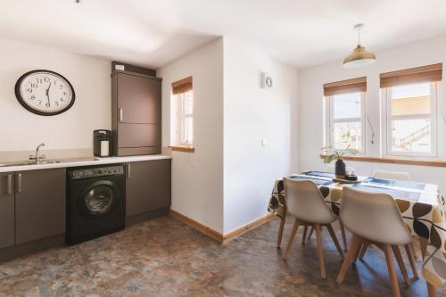 a kitchen and dining room with a table and a clock at Apartment - Sleeps 4 Pet friendly & Free parking in Anstruther