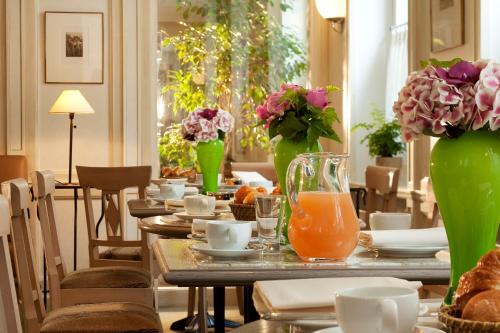a table with plates and vases with flowers on it at Hôtel De l'Arcade in Paris