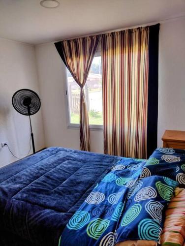a bedroom with a blue bed and a window at La Casita in Embalse