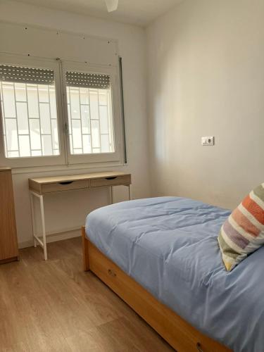 a bedroom with a bed and a desk and two windows at Descanso del GUERRERO in San Miguel de Fluviá