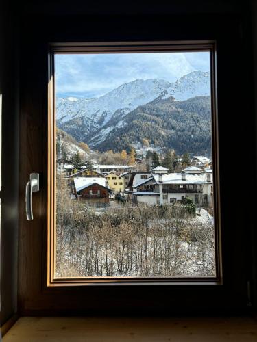 a window with a view of a town and mountains at Alpine Chic Retreat in Courmayeur