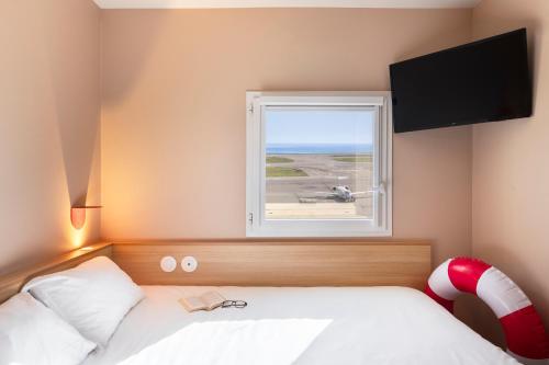 a bedroom with a bed and a window with a plane at Greet Hotel Nice Aéroport Promenade des Anglais in Nice