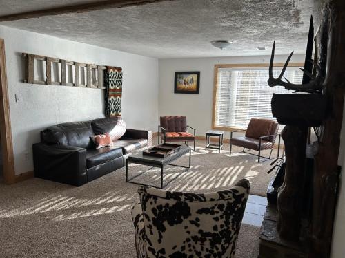 a living room with a black leather couch and chairs at Chinook Winds Lodge in Dubois