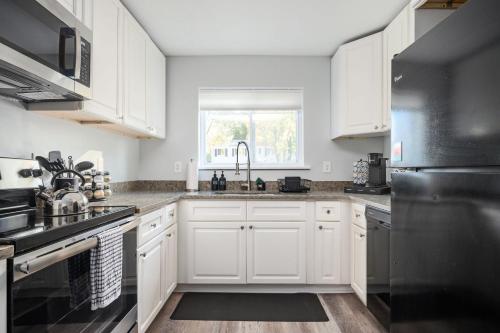 a kitchen with white cabinets and a black refrigerator at Quiet & Quaint apartment, 5 mins to airport and 15 mins to downtown in Atlanta