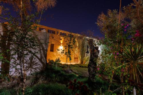 a stone house with a lit up door at night at Olive Garden House Siwa in Siwa
