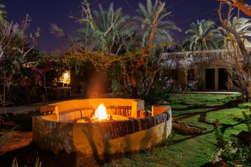 a fire pit in the yard of a house at night at Olive Garden House Siwa in Siwa