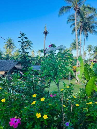 a garden with colorful flowers and palm trees at Lone Traveler Beach View Room in Caridad