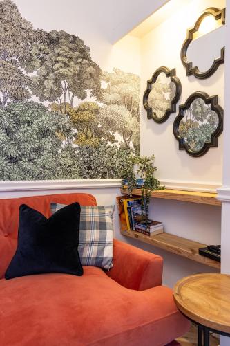 an orange couch in a living room with a wall mural at The Wee Gem in Inverness