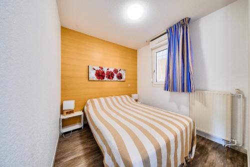 une chambre avec un lit avec une couverture rayée dans l'établissement Résidence les Hauts de Balaruc - maeva Home - Appartement 2 pièces 4 personnes - Budget MAE-5791, à Balaruc-les-Bains