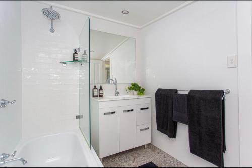 Un baño blanco con bañera y lavabo. en Cowra Cottage, en Cowra