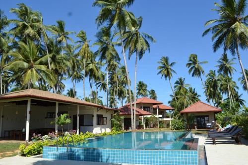 a resort with a swimming pool and palm trees at Lanka Beach Boutique Bungalows & Grand Villa in Tangalle