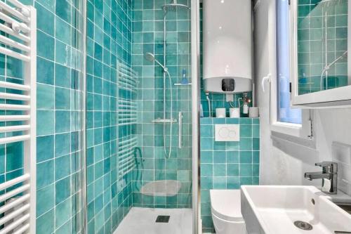 La salle de bains est pourvue de carrelage bleu, d'une douche et d'un lavabo. dans l'établissement Cozy Nest - Montmartre Caulaincourt, à Paris