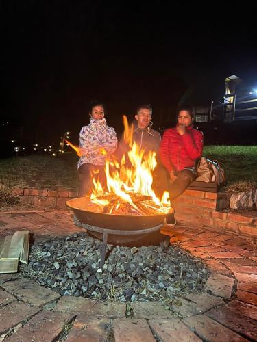three people sitting around a fire pit at night at Glamping Brillo de Luna in Guatavita