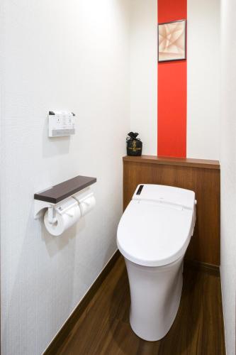 a bathroom with a white toilet and a red wall at Hotel Bellclassic Tokyo in Tokyo