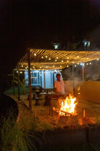 a man sitting under a pergola next to a fire at Alam Nirwana in Gretek