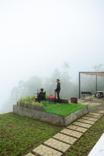 two people sitting on a bench in the fog at Alam Nirwana in Gretek