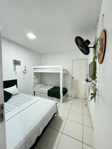 a white bedroom with a bed and a mirror at Âncora Suítes Arraial do Cabo in Arraial do Cabo