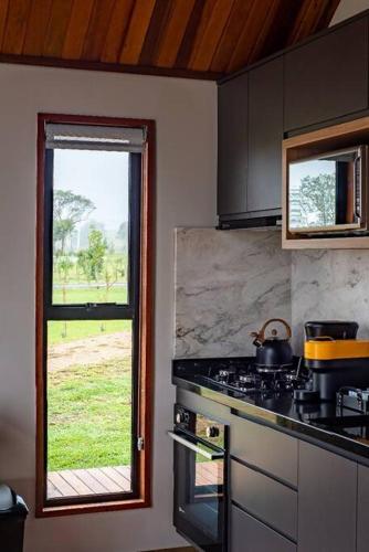 a kitchen with a stove and a window at Cabanas Purunã Ipê-Amarelo in Balsa Nova