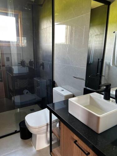 a bathroom with a white toilet and a sink at Cabanas Purunã Ipê-Amarelo in Balsa Nova