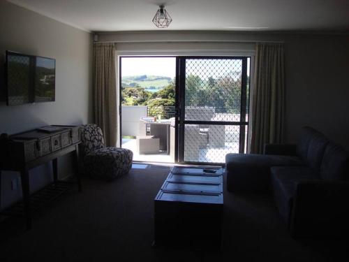 a living room with a couch and a large window at Skyline Apartments - Upper Apartment in Raglan