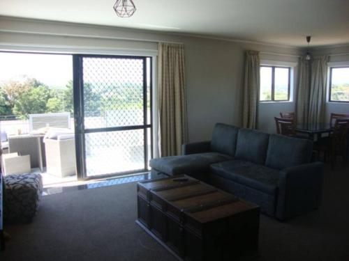 a living room with a blue couch and a sliding glass door at Skyline Apartments - Upper Apartment in Raglan