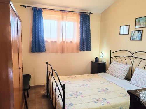 a bedroom with a bed with blue curtains and a window at Apartment in Umbria near Montefalco Winery in Giano dellʼUmbria