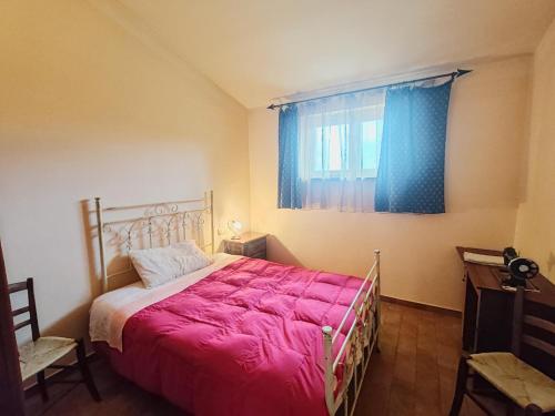 1 dormitorio con 1 cama con edredón rojo y ventana en Apartment in a farmhouse with swimming pool, en Giano dellʼUmbria