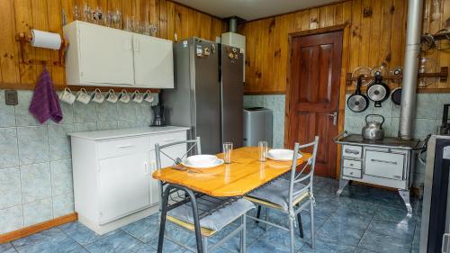 a kitchen with a table with chairs and a refrigerator at Maravillosa cabaña Panguipulli in Panguipulli
