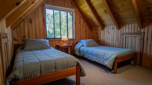 a bedroom with two beds in a log cabin at Maravillosa cabaña Panguipulli in Panguipulli