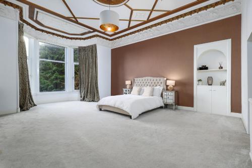 a bedroom with a white bed and a large window at Extravagant 6 Bed Victorian Townhouse with Hot Tub in Glasgow