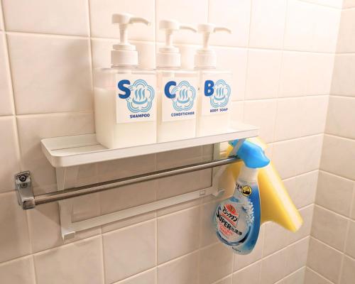 a bathroom with three bottles of cleaning products on a shelf at The Global West in Niihama
