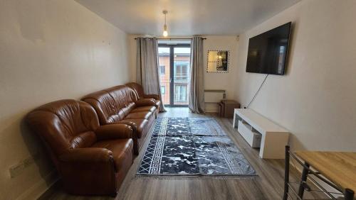 a living room with a leather couch and a television at City Bliss Great Location in Birmingham