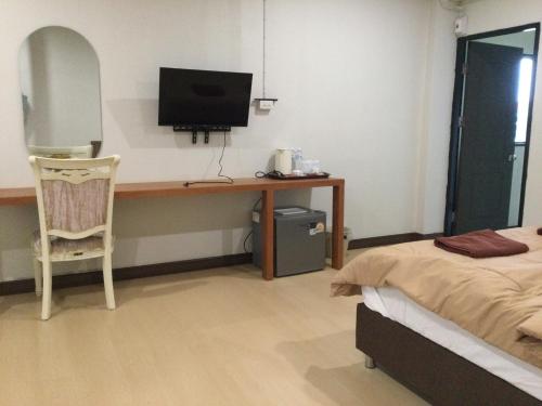 a bedroom with a desk with a television and a bed at theriverhouse in Ban Muang Nga
