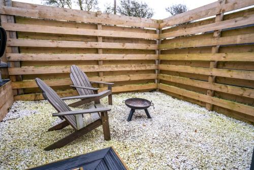 a patio with two chairs and a stool next to a fence at Portside Pasture - (Luxury Cabin) in Portpatrick