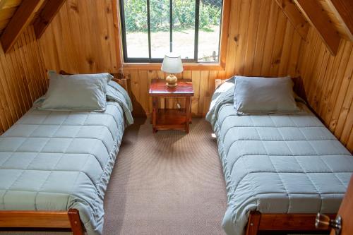 two beds in a room with a table and a window at Maravillosa cabaña Panguipulli in Panguipulli