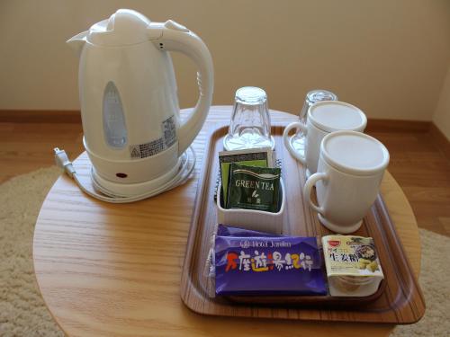 a wooden table with a tray of food and a tea kettle at Manza Hotel Juraku in Tsumagoi