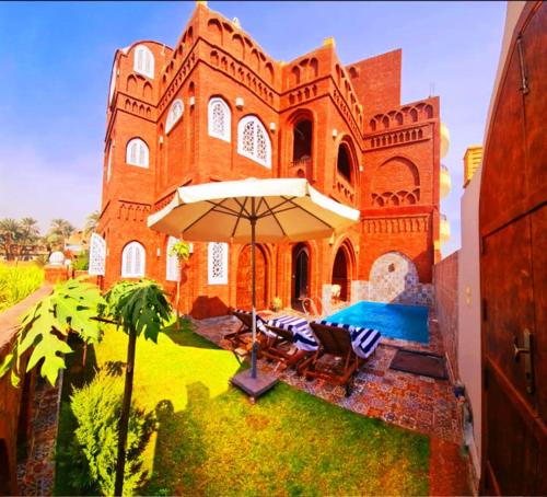 a large brick building with an umbrella in the yard at Luxor Tower in Luxor