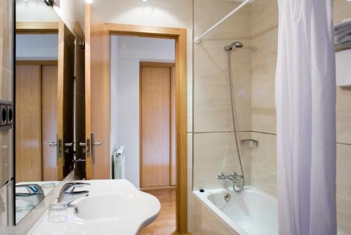 ein Badezimmer mit einem Waschbecken, einer Badewanne und einer Dusche in der Unterkunft Posada del Almudí in Daroca