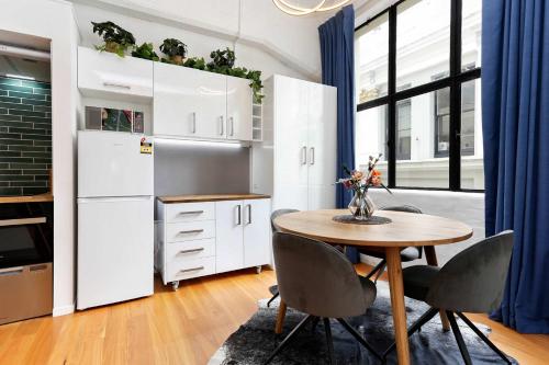 a kitchen with white cabinets and a wooden table at Studio Loft Apartment w bikes Wifi CBD in Auckland