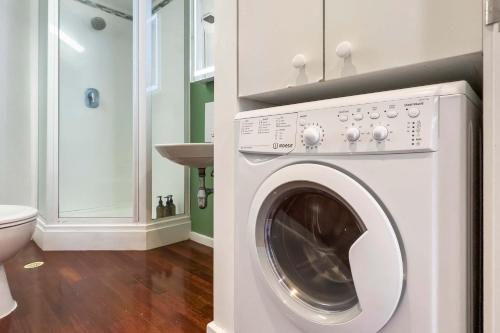 a white washing machine in a bathroom with a toilet at Studio Loft Apartment w bikes Wifi CBD in Auckland