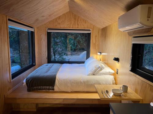 MaipoにあるCabaña en Santuario El Ajial - Paine - Tucu Cabinsの窓2つが備わるドミトリールームのベッド1台分です。