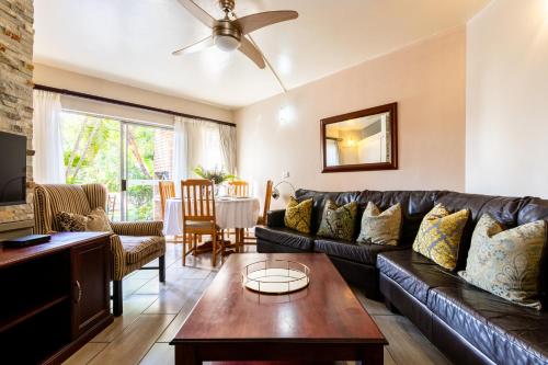 a living room with a leather couch and a table at Perna Perna Lodge St Lucia in St Lucia